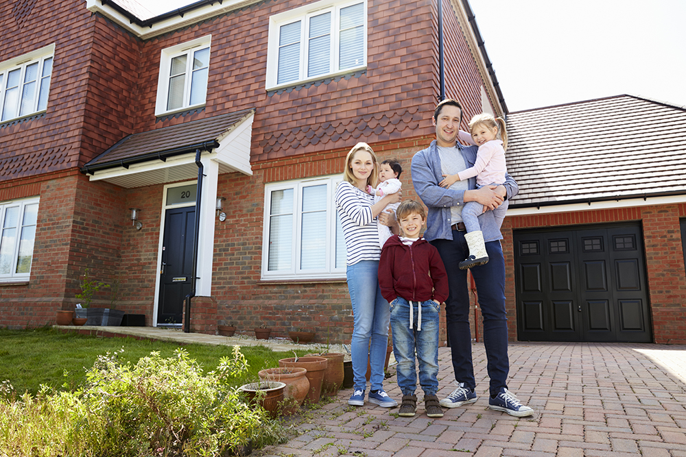 Portrait Of Young Family Standing Outside New Home with Solar